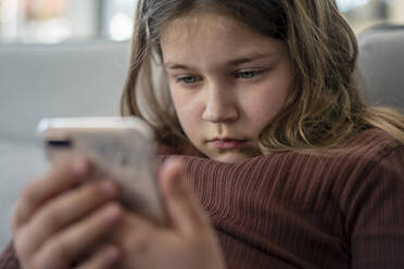Girl using  phone while sitting on sofa - JOSEF01557
