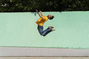 Man jumping mid-air in front of green wall - AFVF06969