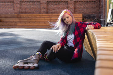 Junge Frau mit gefärbtem Haar und Rollschuhen auf dem Boden sitzend - VPIF02852