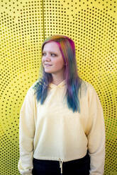 Portrait of young woman with dyed hair in front of yellow wall - VPIF02854