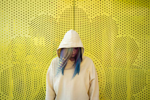 Portrait of young woman with dyed hair in front of yellow wall stock photo