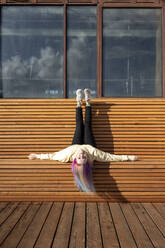 Young woman with dyed hair lying on wooden bench - VPIF02860