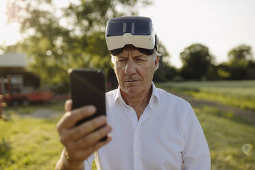 Mann benutzt Smartphone und trägt VR-Brille im Hof - GUSF04361