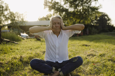 Man practicing yoga while sitting in backyard stock photo