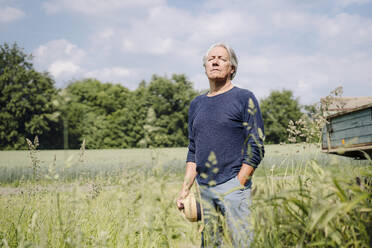 Zerknitterter Mann mit Hut im Hof stehend - GUSF04403