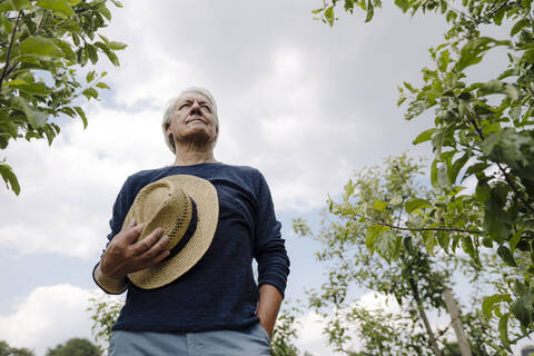 Man holding hat standing against sky in field stock photo