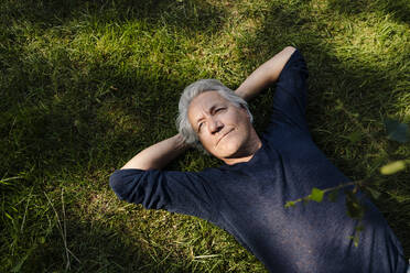 Confident smiling man lying down in field - GUSF04433