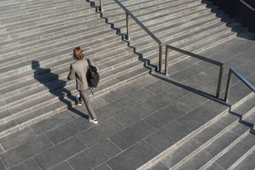 Geschäftsmann mit Tasche bewegt sich auf einer Treppe in der Innenstadt während eines sonnigen Tages - VPIF02928