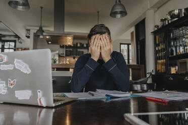 Overstressed young man studying from home, covering face with his hands - MFF06026