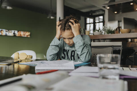 Schoolboy learning at home, head in hands, solving problem stock photo