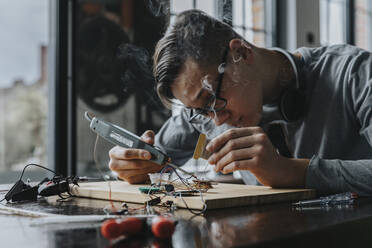 Young man tinkering with soldering iron at home - MFF06061