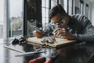 Young man tinkering with soldering iron at home - MFF06062