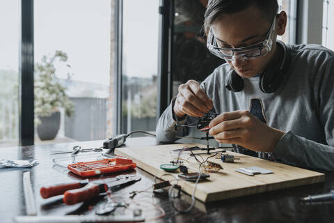 Young man tinkering with soldering iron at home stock photo