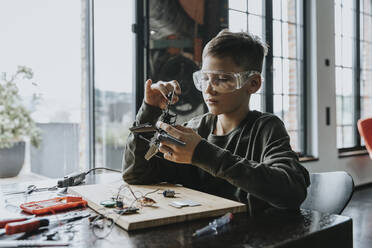 Boy assembling miniature helicopter at home - MFF06064