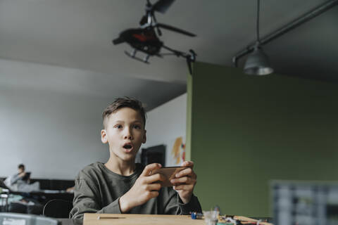 Junge steuert Miniaturhubschrauber mit einer App, lizenzfreies Stockfoto