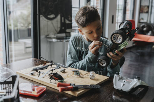 Junge beim Zusammenbau eines ferngesteuerten Spielzeugautos mit Schraubenzieher - MFF06073