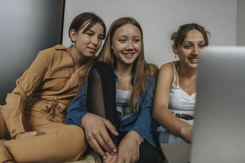 Eine Gruppe von Freundinnen sitzt auf dem Bett und schaut einen Film auf dem Laptop - MFF06077