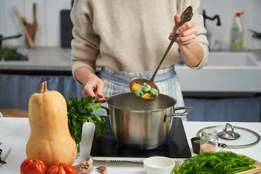 Anonyme weibliche Köchin beim Kochen von Knödeln mit buntem Teig - ADSF11745