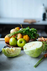Bündel verschiedener frischer Früchte und Gemüse auf der Theke während der Zubereitung des Mittagessens in einer modernen Küche - ADSF11800