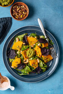 Draufsicht auf einen Teller mit gesundem veganem Salat und Gabel auf einem blauen Tisch in der Küche - ADSF11810