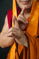 Gestürzte tibetische Frau in traditioneller Kleidung mit Gebetsperlen, die mit den Händen eine Mudra-Geste macht - ADSF11872