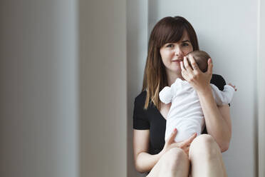 Young woman holding her baby girl at home - SAJF00035