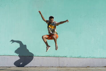 Casual man jumping in front of colorful wall - AFVF06987