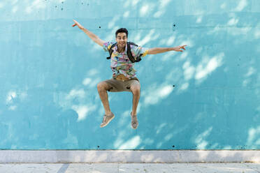 Casual man jumping in front of blue wall - AFVF07003