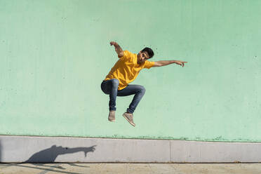 Casual man jumping in front of colorful wall - AFVF07008