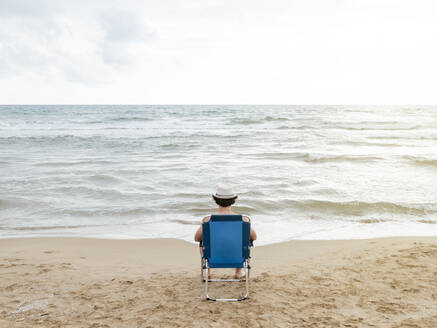 Rückansicht eines Mannes in einer Strandliege am Strand - JCMF01173