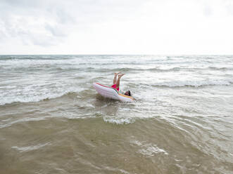 Mann beim Baden im Meer auf einem aufblasbaren Schwimmkörper, der umkippt - JCMF01176