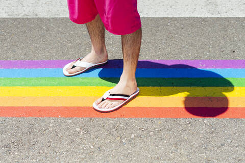 Mann steht auf einem Fußgängerüberweg in Regenbogenfarben, lizenzfreies Stockfoto