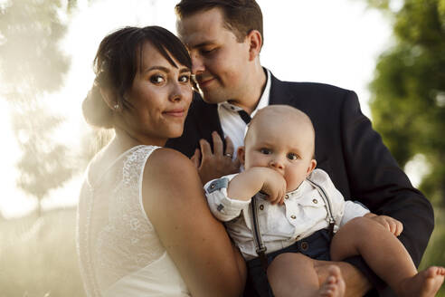 Schöne junge Braut mit Bräutigam und Sohn bei der Hochzeit bei Sonnenuntergang - SAJF00065