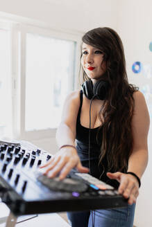 Lächelnde schöne weibliche Club-DJ mit Audio-Ausrüstung im Studio - MRRF00281