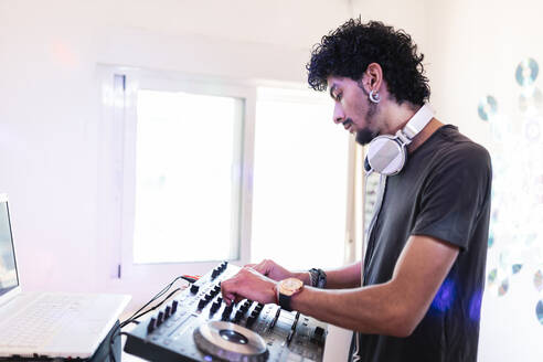 Junger männlicher Musiker, der in einem Aufnahmestudio als DJ den Ton mischt - MRRF00289