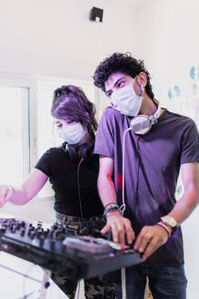 DJ-Paar mit Gesichtsmasken beim Abmischen im Tonstudio - MRRF00304