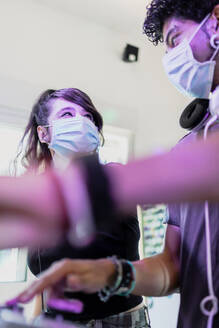 DJ-Paar mit Gesichtsmasken, das sich im Aufnahmestudio ansieht - MRRF00307