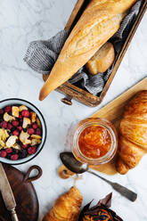 Komposition aus frischem Baguette und Croissants, serviert mit aromatischer süßer Aprikosenmarmelade auf einem Marmortisch (Draufsicht) - ADSF12012