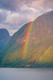 Mysteriöse Landschaft von bunten Regenbogen in felsigen Bergen in ruhigem Wasser unter bewölktem Himmel in Norwegen - ADSF12075