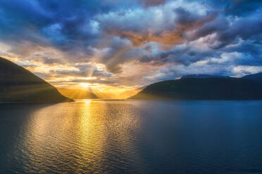 Große erstaunliche Landschaft von Sonnenlicht durch bewölkten Himmel auf wellenförmigen Wasser zwischen felsigen Bergen in Norwegen - ADSF12077