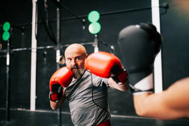 Cropped unerkennbar junge Sportlerin Athleten in Boxhandschuhen Training Kampf mit professionellen männlichen Trainer in modernen Fitness-Studio - ADSF12108