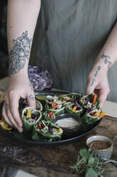 Young woman preparing vegan roll with vegetables and yoghurt sauce - ALBF01372