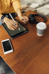 Mittelteil einer jungen Studentin, die am Tisch eines Straßencafés ein digitales Tablet benutzt - BOYF01373