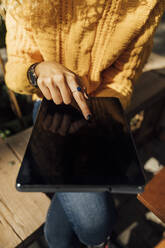 Mittelteil einer jungen Frau, die in der Stadt ein digitales Tablet benutzt - BOYF01380