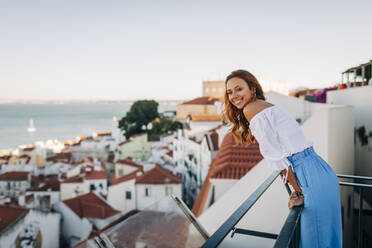 Junge Frau lächelt, während sie auf einem Dach in Alfama, Lissabon, Portugal steht - DCRF00671