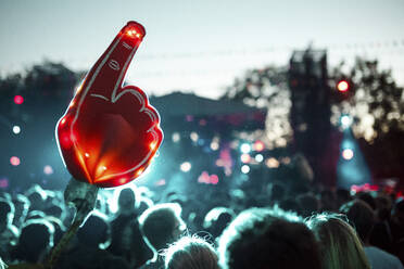 Large foam hand over crowd of people having fun during music festival - SAJF00066