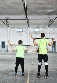 Father and son holding hockey sticks at sports court - VEGF02824