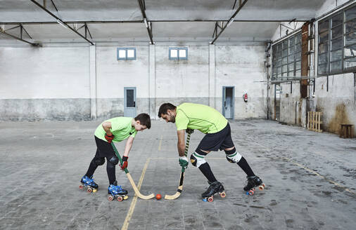 Father and son in face off while playing roller hockey on court - VEGF02827