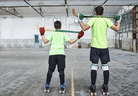 Father and son in sports uniform holding hockey sticks at court - VEGF02831