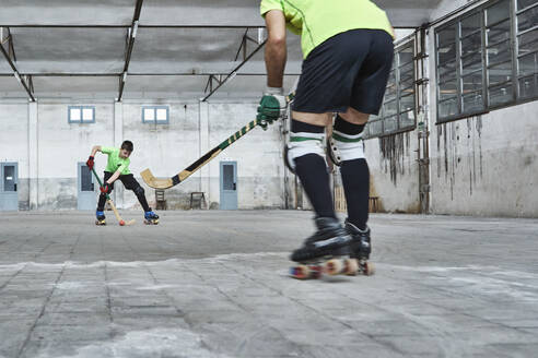 Father and son playing roller hockey on court - VEGF02832